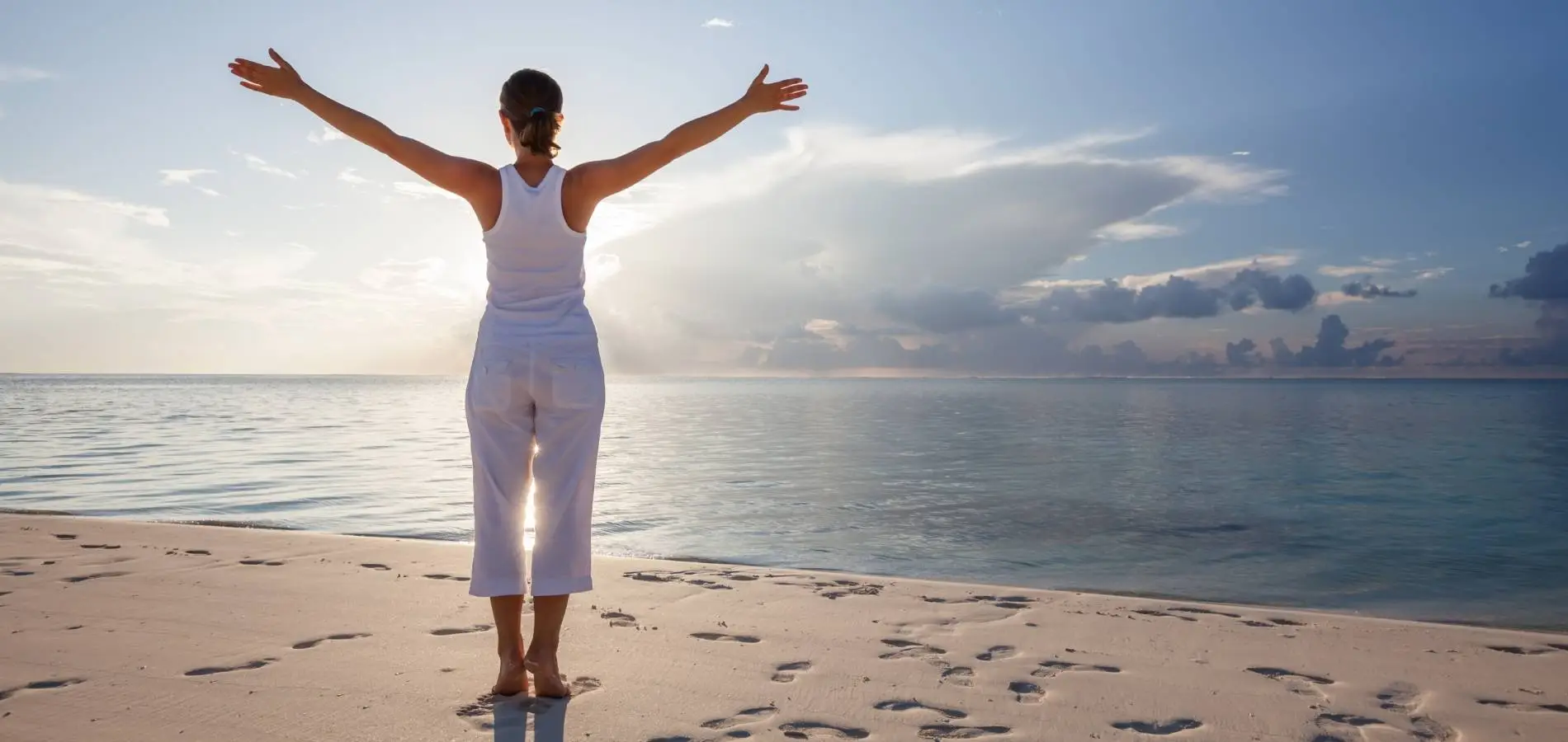 Femme écartant les bras face à la mer